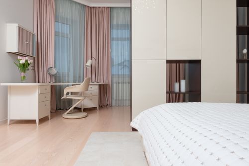 Free Contemporary interior of large bedroom with white wardrobe and soft bed near table with chair Stock Photo