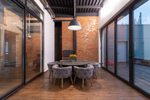 Contemporary dining room with brick walls and large windows offering outdoor views.