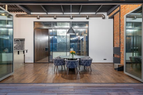 Interior of spacious dining room with round table and comfortable soft chairs placed in modern apartment