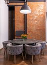 Dark round table and comfortable armchairs against brick wall in room