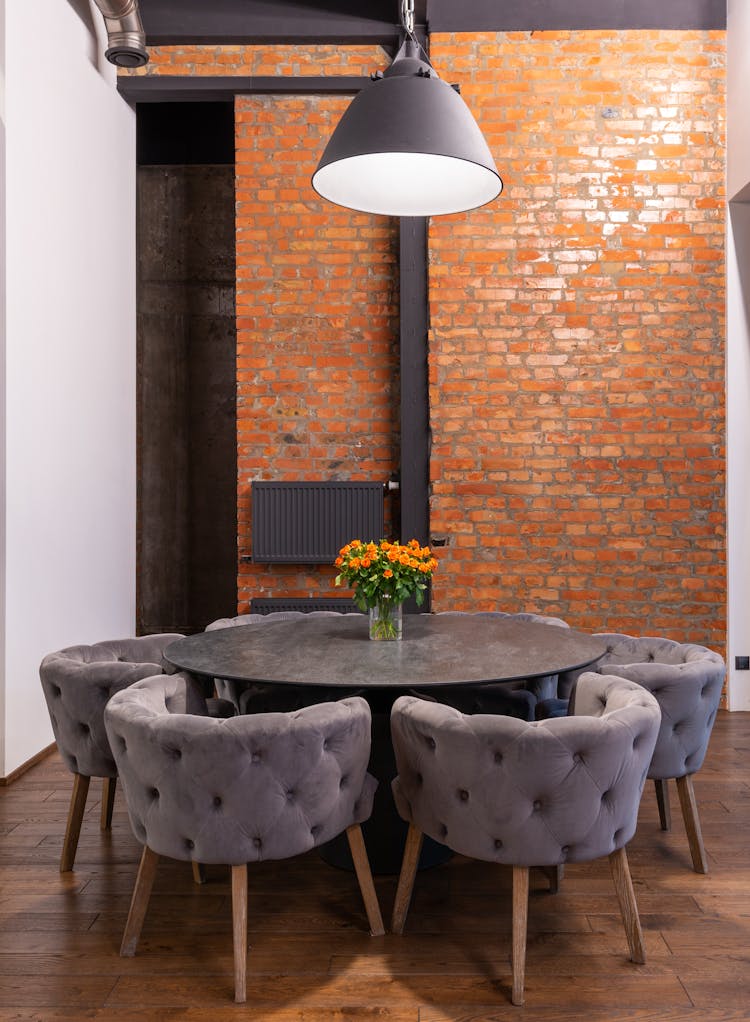 Dark Round Table And Comfortable Armchairs Against Brick Wall In Room