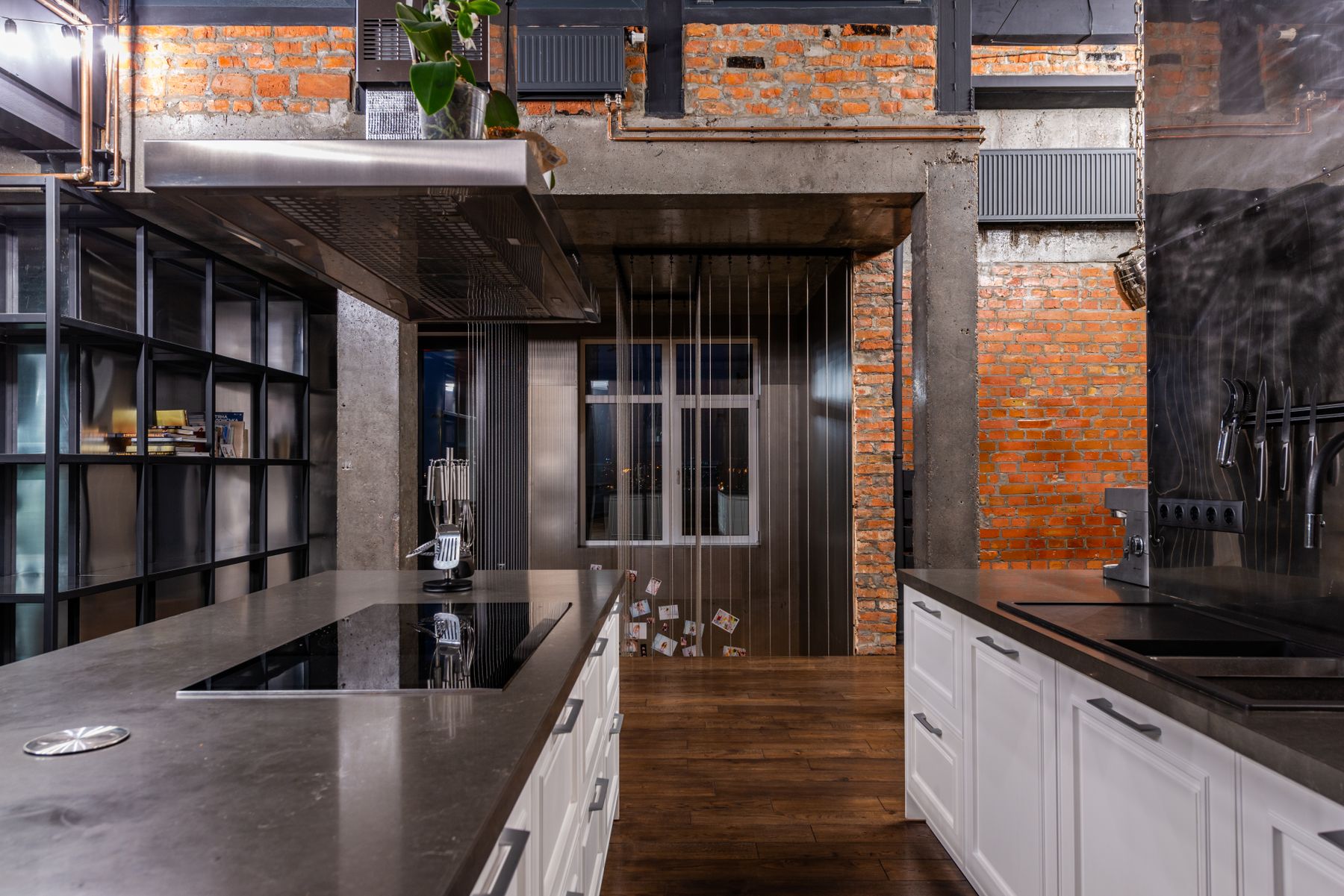 Kitchen with exposed orange brick, concrete framing, stainless extractor and dark counters