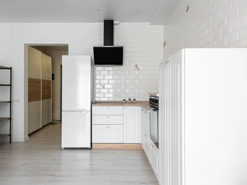 Contemporary kitchen with refrigerator and range hood against a white brick wall Contemporary kitchen with refrigerator and range hood against a white brick wall