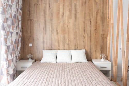 Contemporary bedroom interior with bed against wooden wall