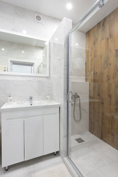 Creative design of bathroom with washbasin between cabinet and mirror against glass door of shower room in light house