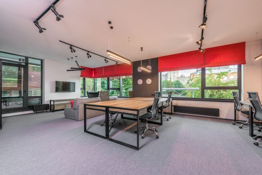 Modern open-plan office interior with desks, ergonomic chairs, pendant lamps and large windows