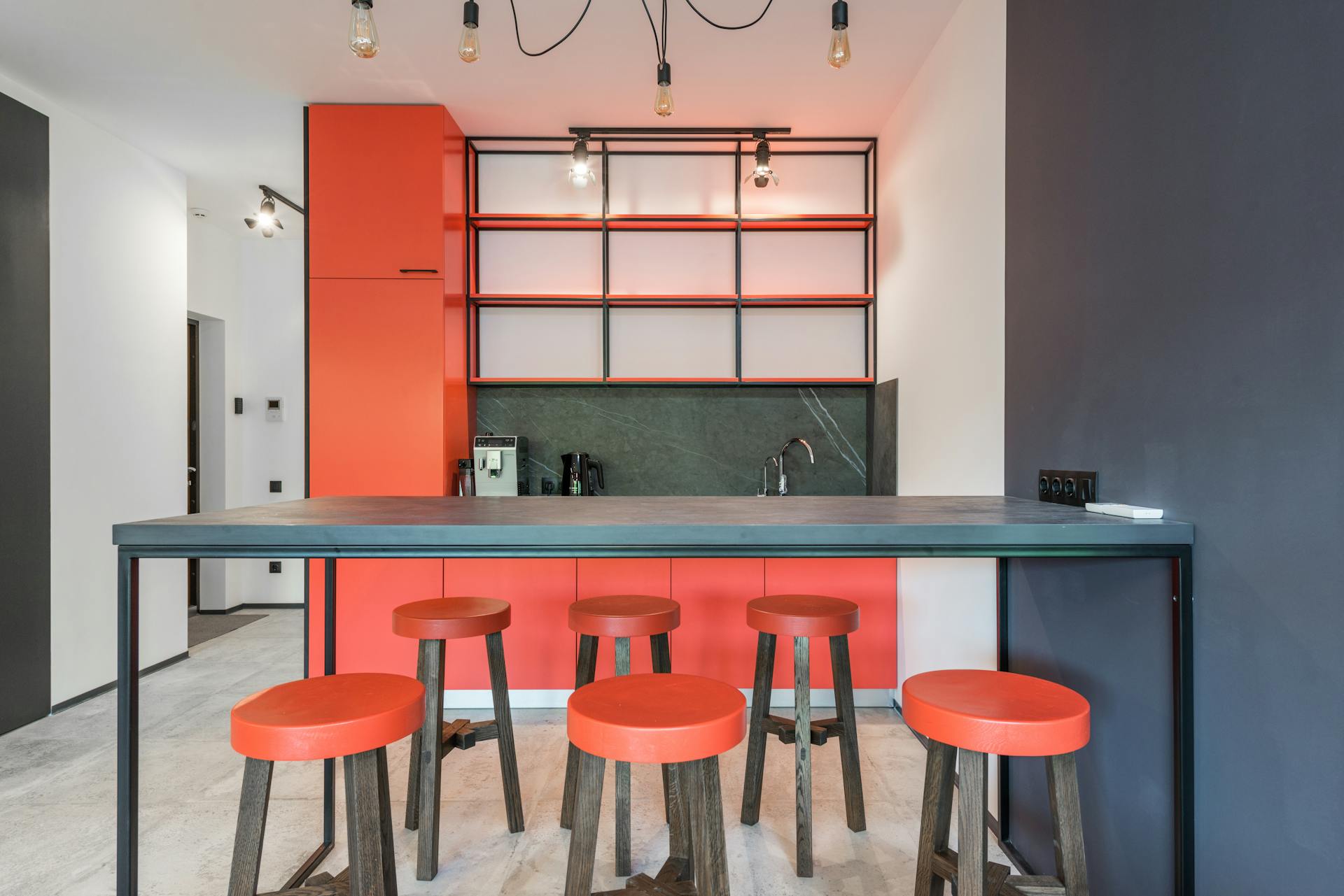 Contemporary kitchen with table and chandelier against empty shelves above coffee machine in light house