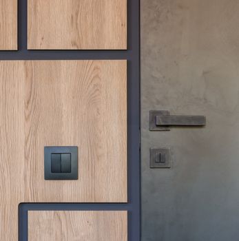 Details of interior of modern apartment with gray metal door and dark switch in corridor