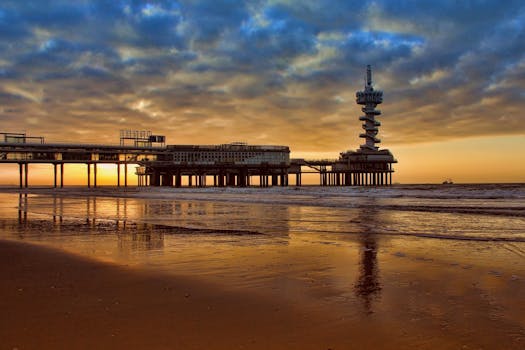 A tranquil sunset view at the pier, reflecting vivid colors on the sea and sand.