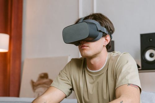 Free Young man using VR headset indoors, exploring virtual reality with focus and engagement. Stock Photo