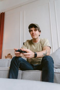 A man sitting on a couch playing video games, focused and enjoying leisure time.