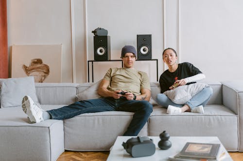 A Man and Woman Playing Video Games while Sitting on the Couch