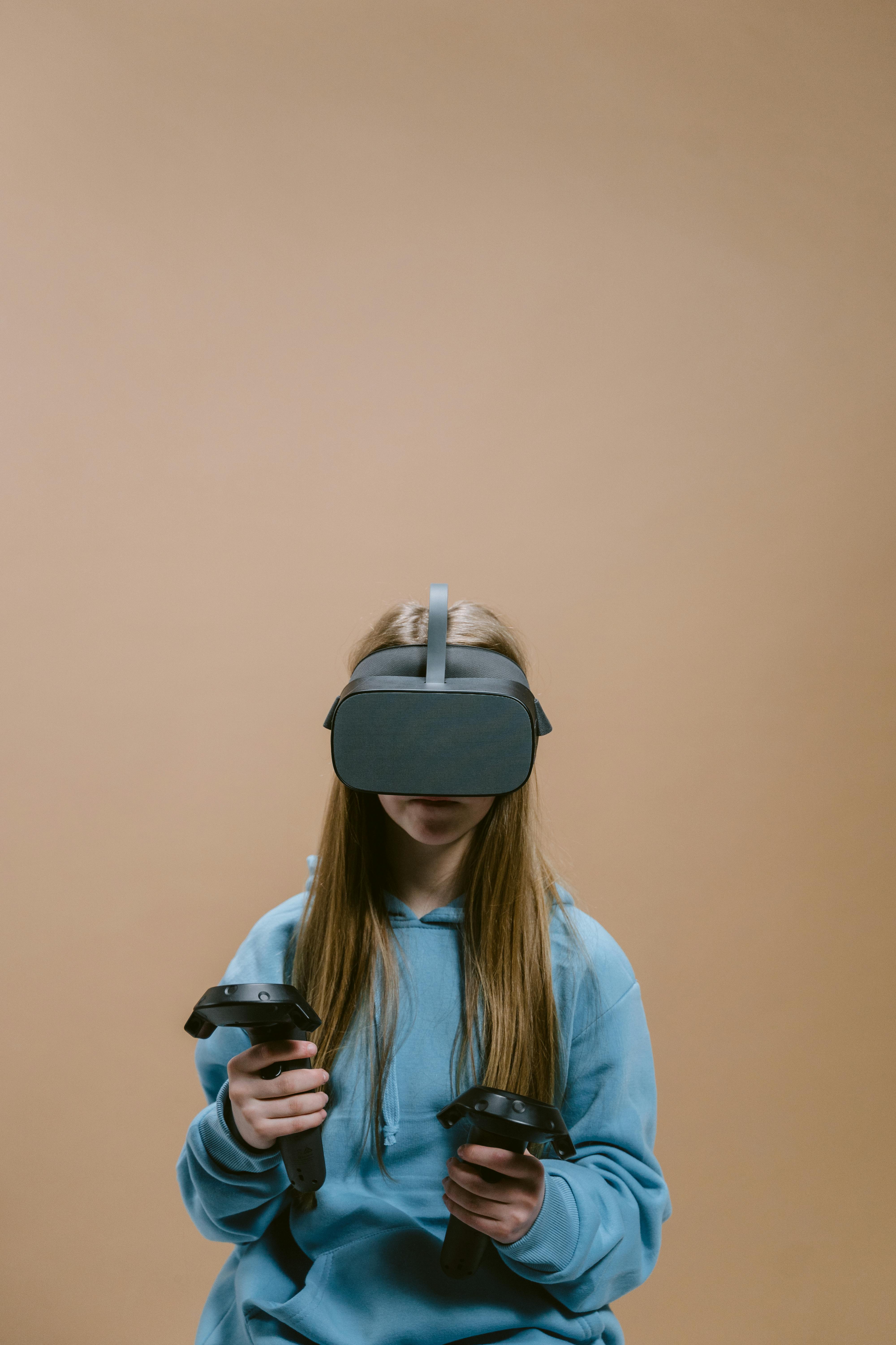 a woman in blue jacket using virtual reality goggles and controllers