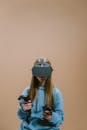 A Woman in Blue Jacket Using Virtual Reality Goggles and Controllers