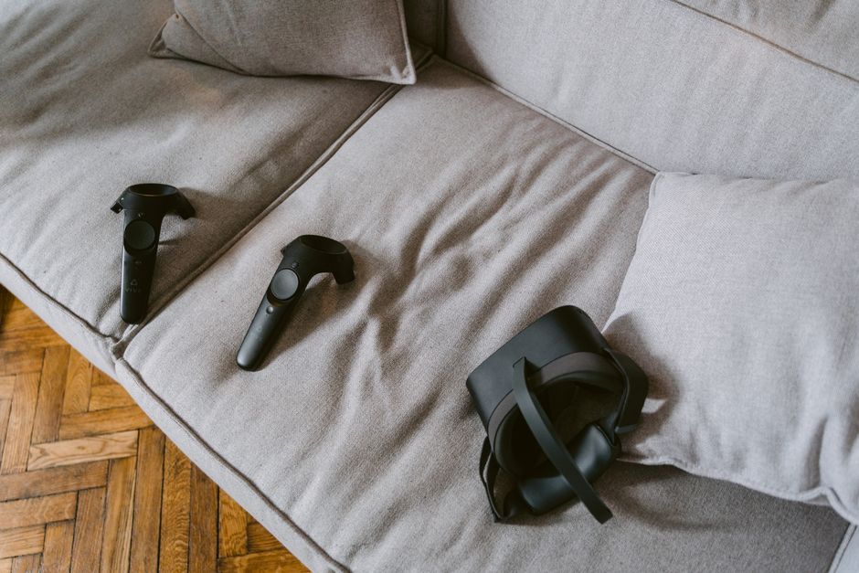 快適なベージュのソファに置かれたVRヘッドセットとコントローラー。