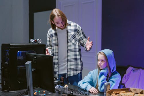 A Man Scolding a Girl Sitting in Front of a Computer 