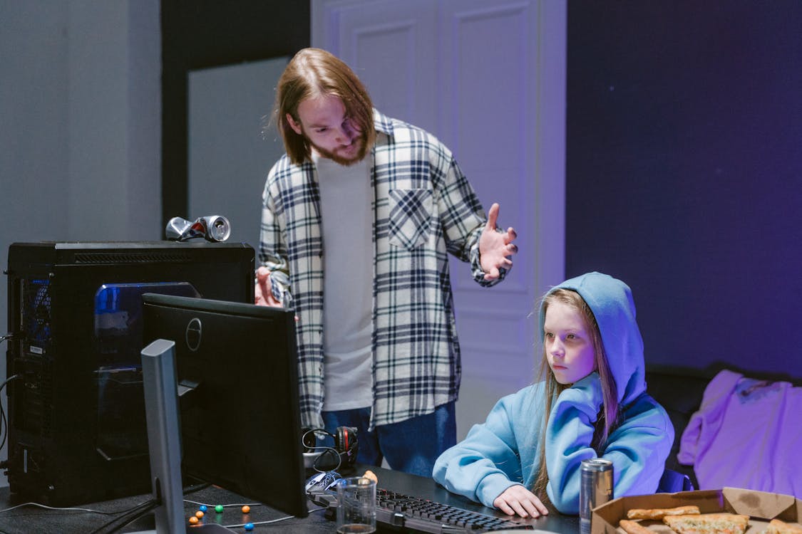 A Man Scolding a Girl Sitting in Front of a Computer 