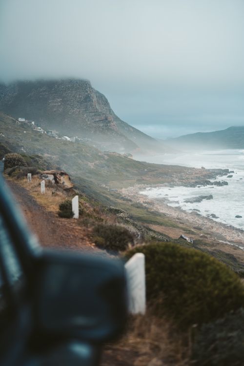 Free Breathtaking view of a coastal road on a misty day with ocean waves crashing. Stock Photo