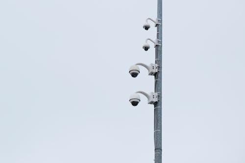 Security Cameras on Metal Pole Under White Sky