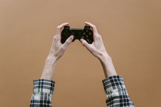 Close-up of hands holding a game controller against a brown background, perfect for gaming themes.