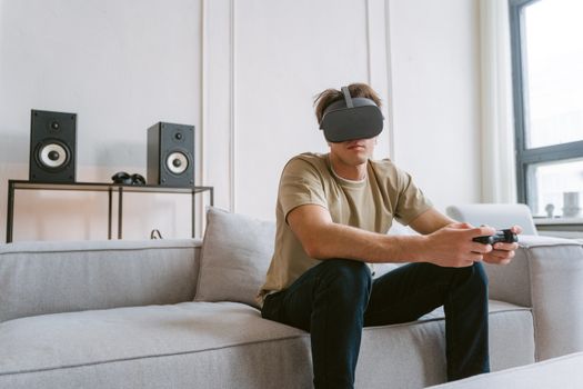 A man enjoys virtual reality gaming on a sofa, using a controller and VR headset.