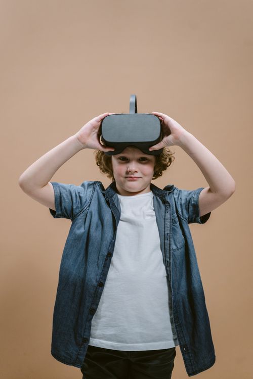 Free Child wearing VR headset on beige background, experiencing virtual reality. Stock Photo
