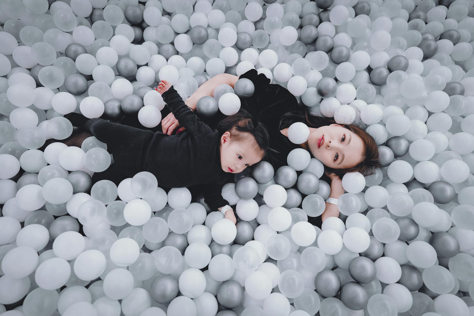 Woman Lying with Toddler in Monochrome Ball Pit