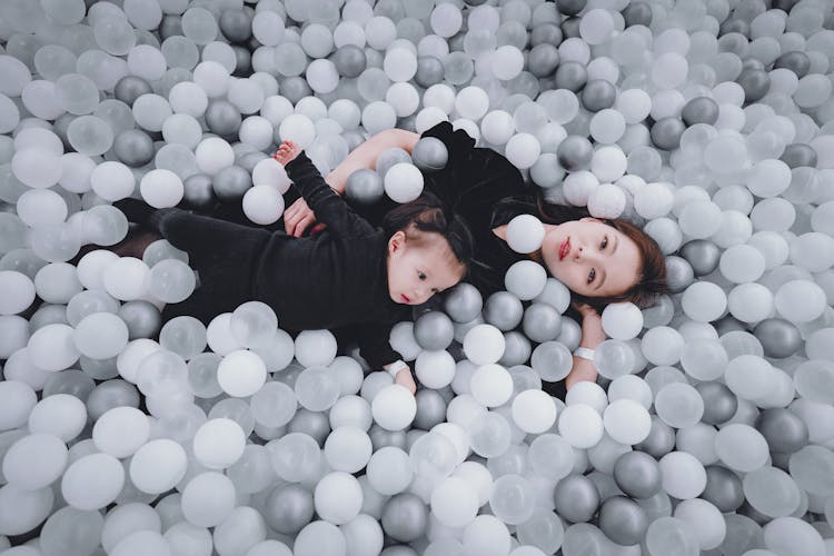 Woman Lying With Toddler In Monochrome Ball Pit