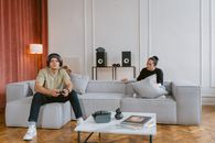 Two young adults in a modern living room, gaming and relaxing on a sofa. Tech-focused lifestyle.
