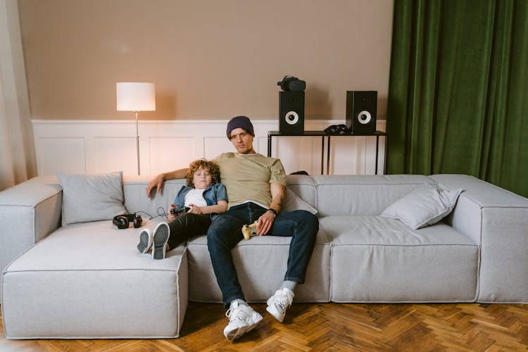 Man And Boy Sitting On Gray Couch