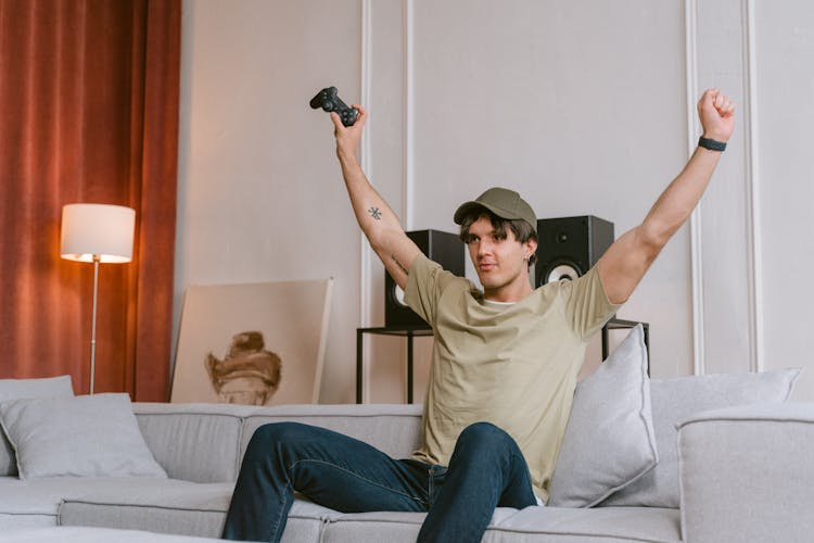 A Man Sitting On Sofa Winning A Video Game