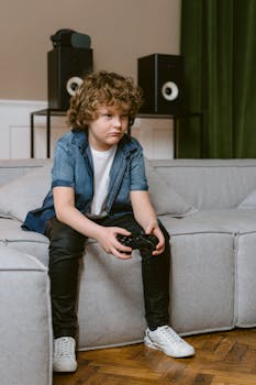 A young boy intensely plays video games while sitting on a couch indoors.