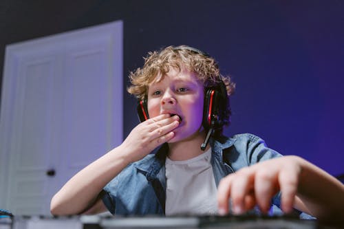 Free A Boy Wearing a Headset Putting Food in Mouth Stock Photo