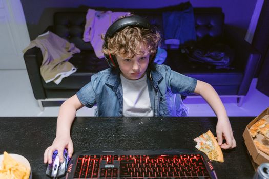 A focused young gamer engages in a nighttime gaming session with snacks and a headset.