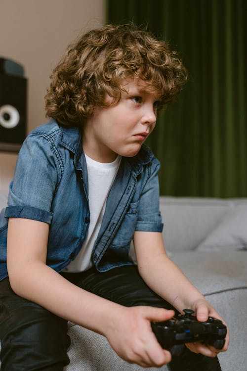 Close-Up Shot of a Boy Holding a Video Game Controller while Sitting on the Sofa