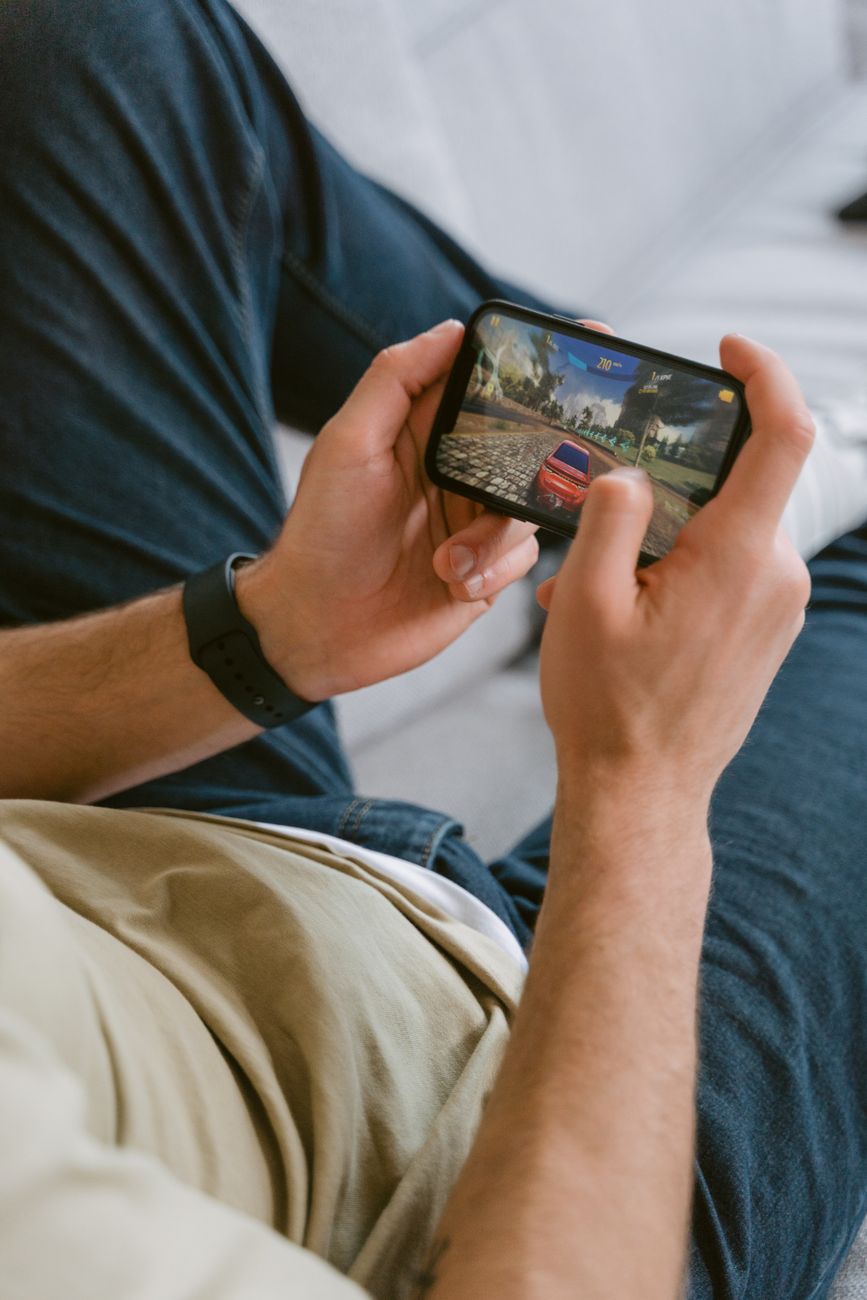A player holding a phone in a low-light room, matching the section on gaming as one part of a broader flagship brief.