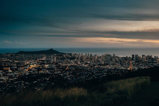 Photo by Aleksey Kuprikov Captivating aerial view of Honolulu's skyline and ocean at dusk, featuring Diamond Head and vibrant city lights.