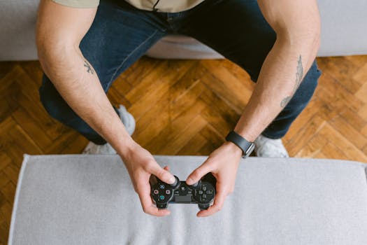 A man sitting on a couch holds a game controller, ready to play video games.