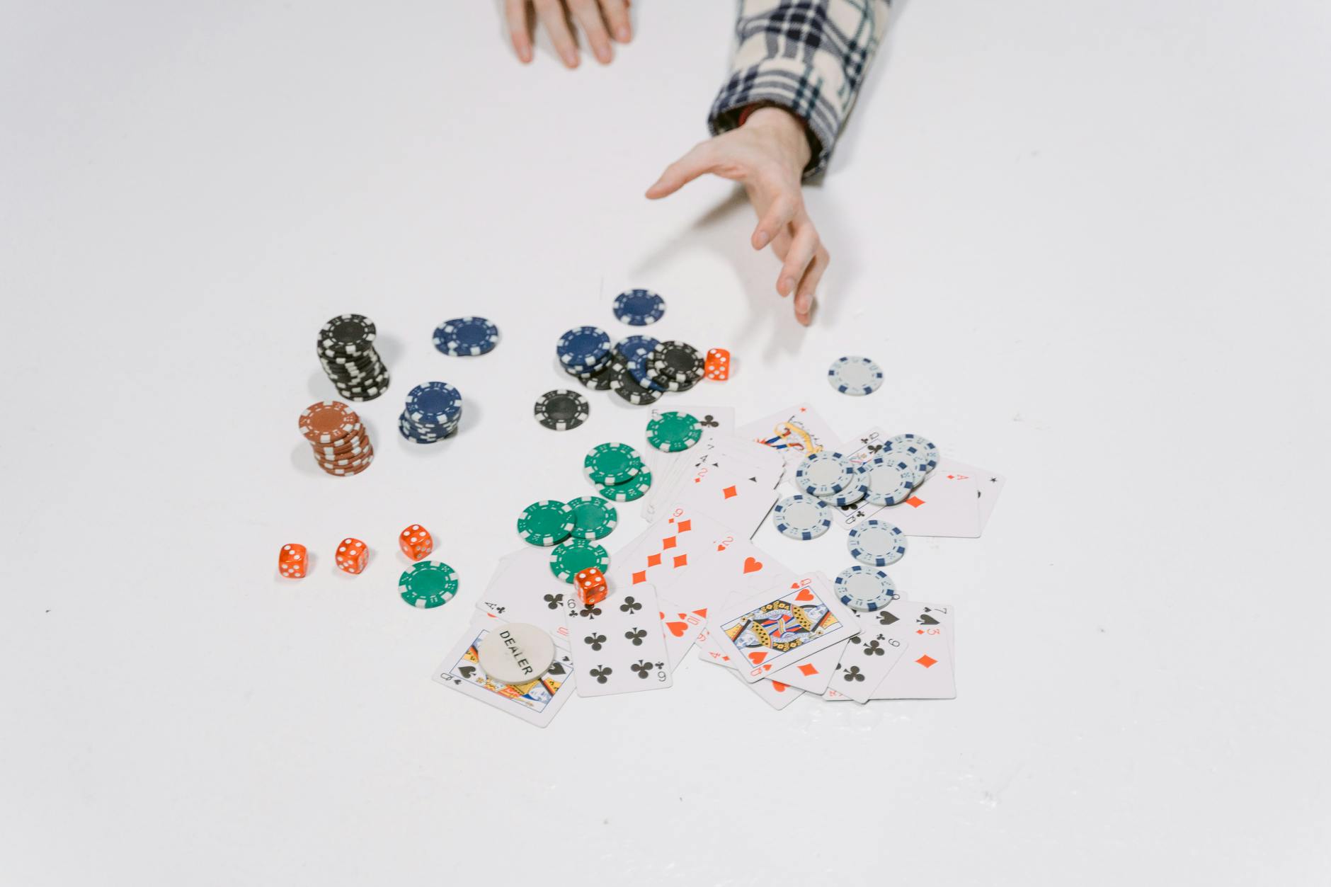 Close-up of poker chips and cards on a white surface, capturing a moment in a card game.