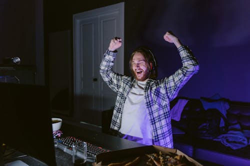 Man in Plaid Shirt Happily Playing a Computer Video Game