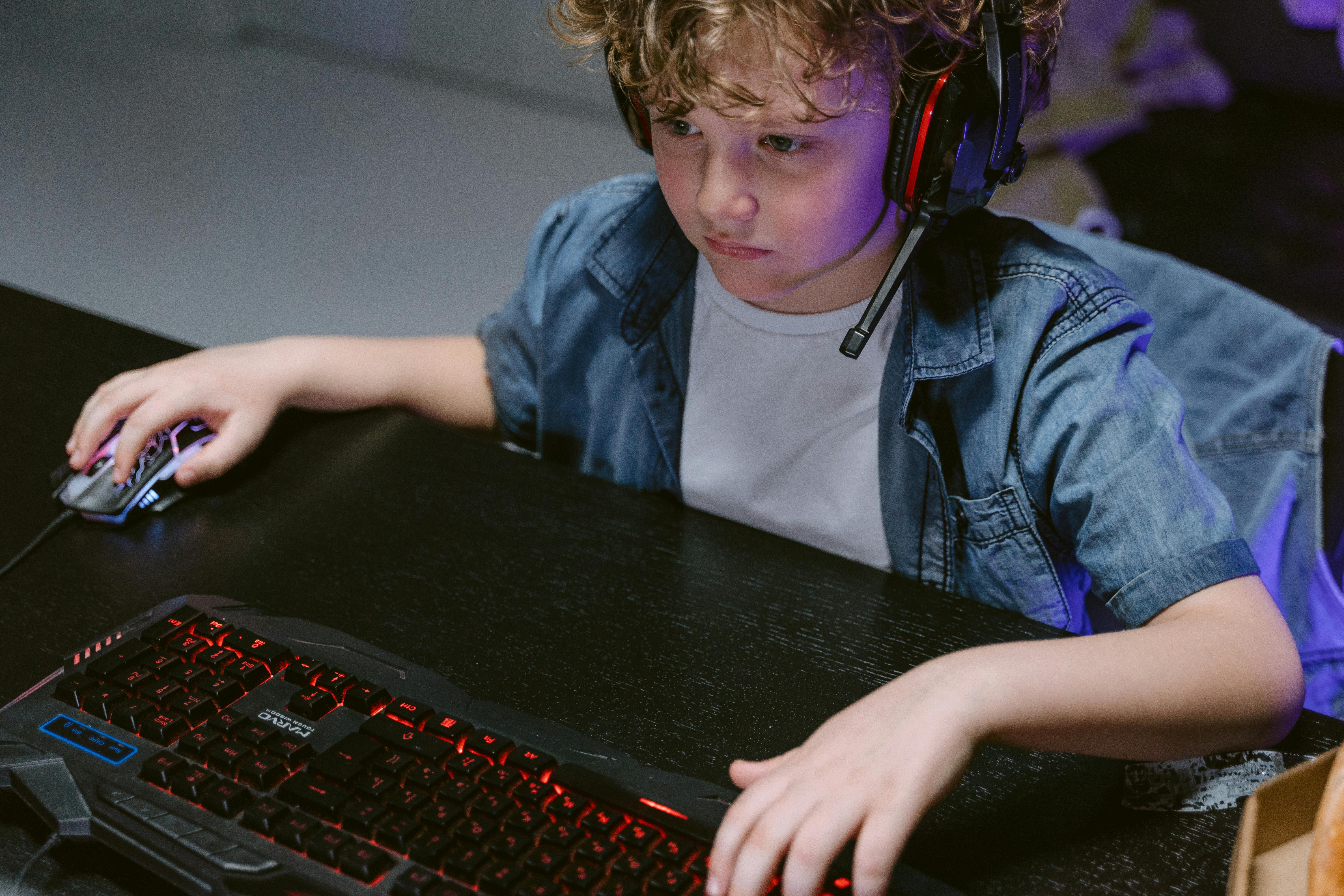 lazy teenager boy play computer games, sit in headphones, looking at screen  of laptop, free time at home Stock Photo