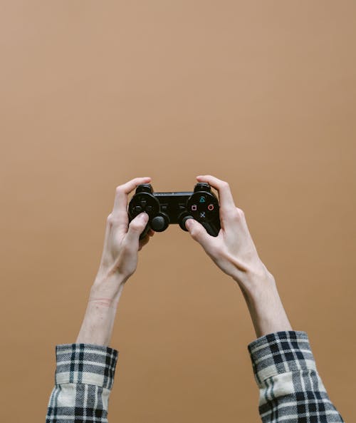 Photos gratuites de console de jeux vidéo, fond marron, mains