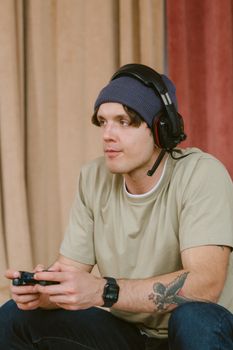 Casual gamer focused on playing video games indoors wearing a headset.