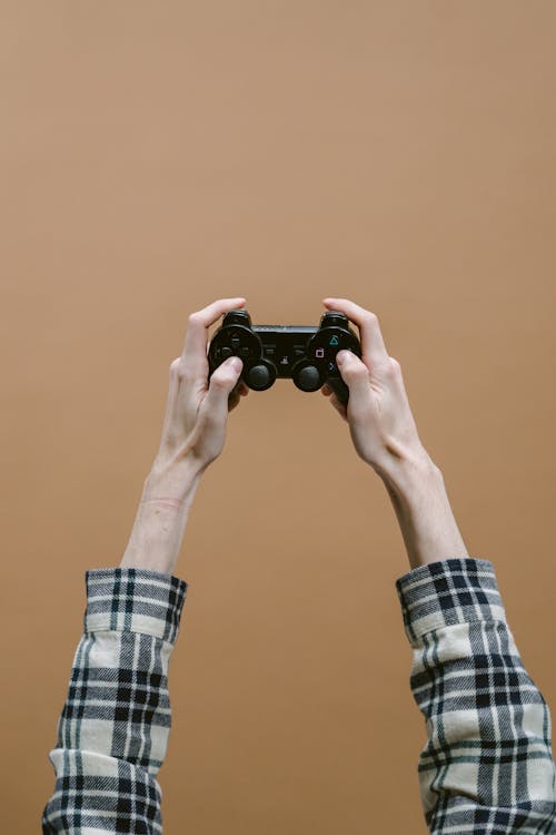 Foto profissional grátis de console de videogame, controle de videogame, fundo marrom