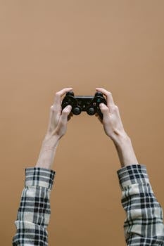 Close-up of hands holding a game controller against a plain brown background.