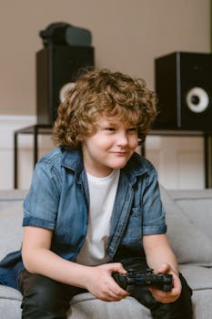 Curly-haired child with a game controller enjoying video games indoors on a sofa.