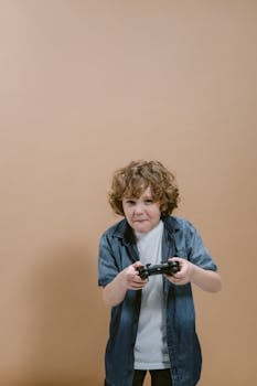 Child intensely playing video game with controller against a plain backdrop in a studio shoot.