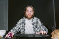 Man in Plaid Long Sleeve Shirt Playing Video Games with a Computer