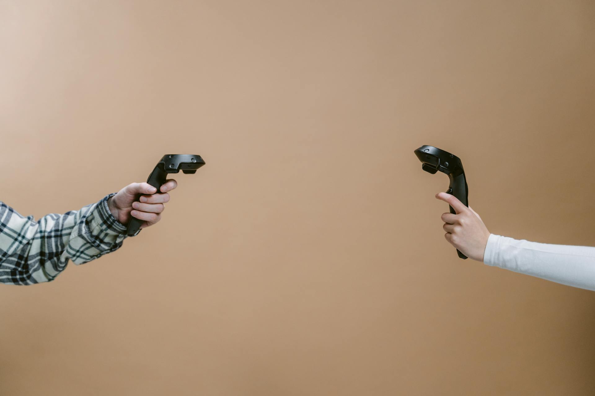 Hands holding game controllers against a brown backdrop, showcasing modern gaming technology.