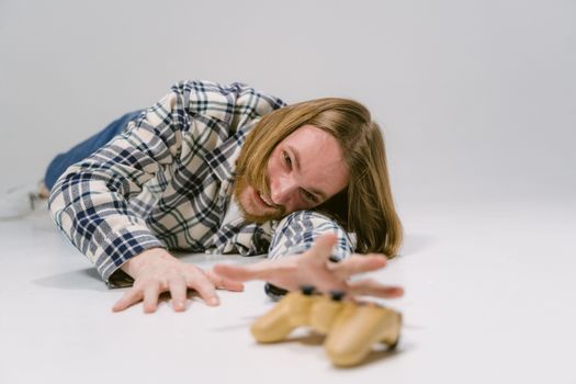 Man in plaid shirt reaching out to grab a gaming controller on a studio floor.